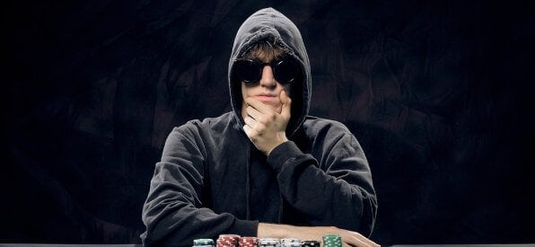 Pokerspieler mit Pokerface, Chips-Stapel und Ass-Paar